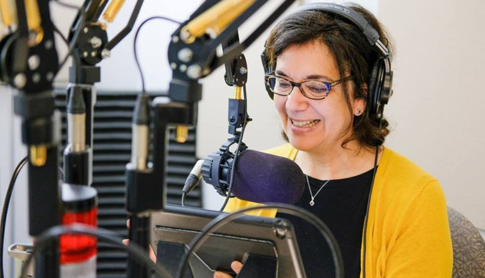 Photo d'Hélène Denis devant un micro de radio.