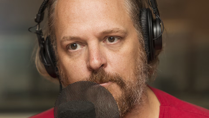 Portrait photo de Fabien Cloutier devant un micro de radio.