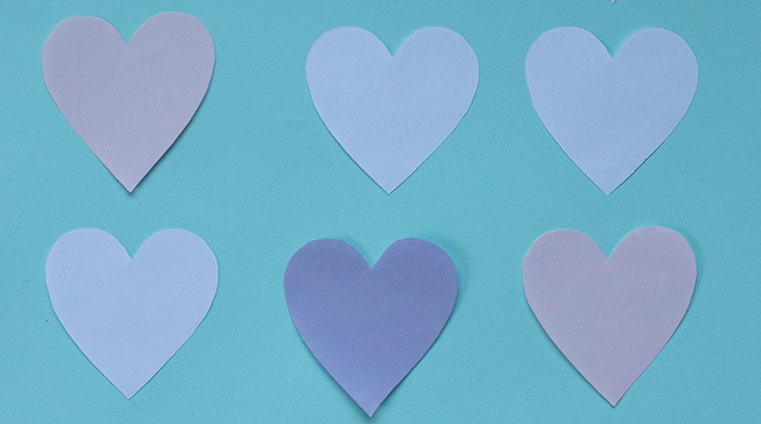Photo d'une série de coeurs en papier posée sur un fond turquoise.