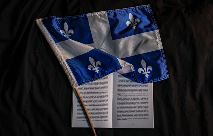 Photo d'un drapeau du Québec posé sur un livre ouvert.