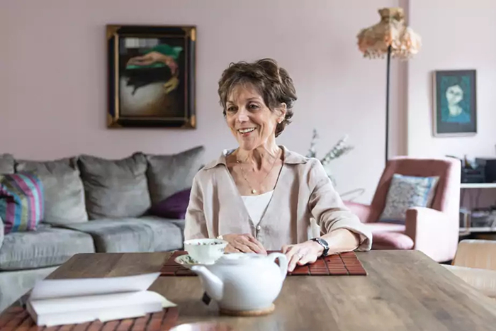 Portrait photo de Francine Pelletier assise à une table devant une théière et une tasse de thé.