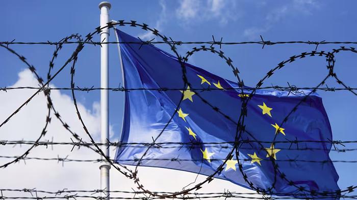 Photo du drapeau de l'Union européenne vu au travers de barbelés.