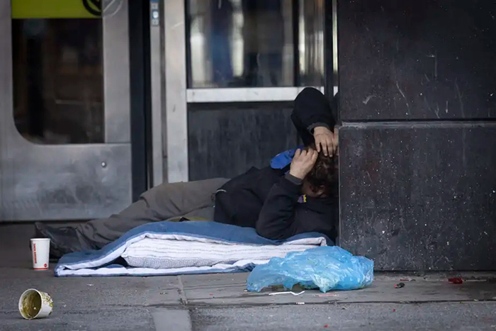 Photo d'un sans-abri couché devant une porte de métro.