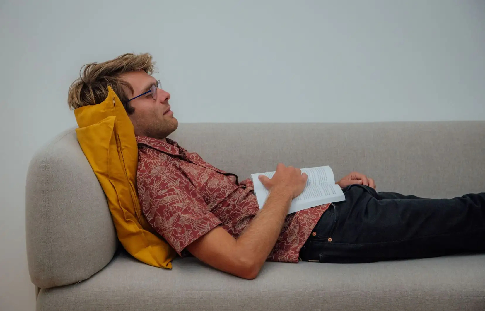 Photo d'un homme couché sur un divan, un livre ouvert sur le ventre.