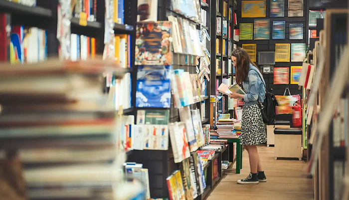 Photo d'une lectrice feuilletant un livre dans une librairie.