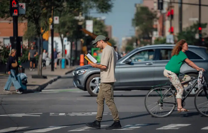 Photo d'un homme traversant une rue tout en lisant un livre.