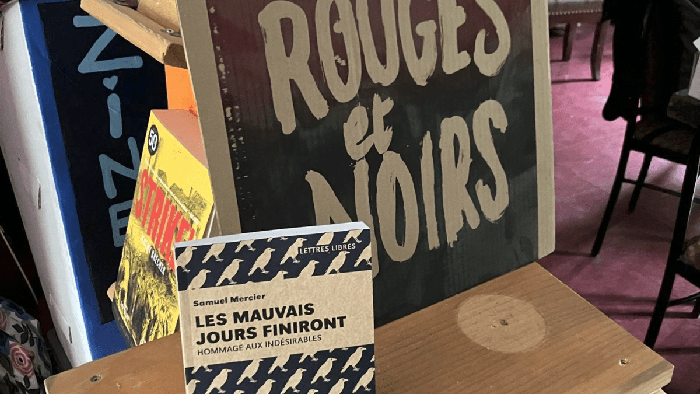 Photo d'une table avec un livre de Lux Éditeur et une affiche de carton disant «Rouges et noirs».