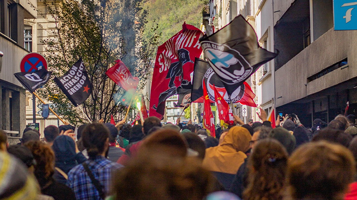 Photo d'une manifestation où sont brandis des drapeaux antifascistes.