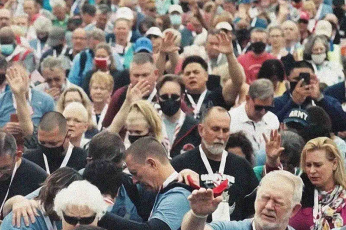 Photo d'une foule d'Américains où certains lèvent les mains en prière.