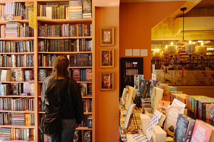 Photo de l'intérieur d'une librairie. Une femme vue de dos regarde un des rayons.