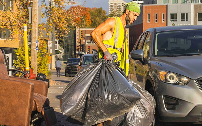 Photo de Simon Paré-Poupart lançant un sac de poubelle dans un camion à ordures.