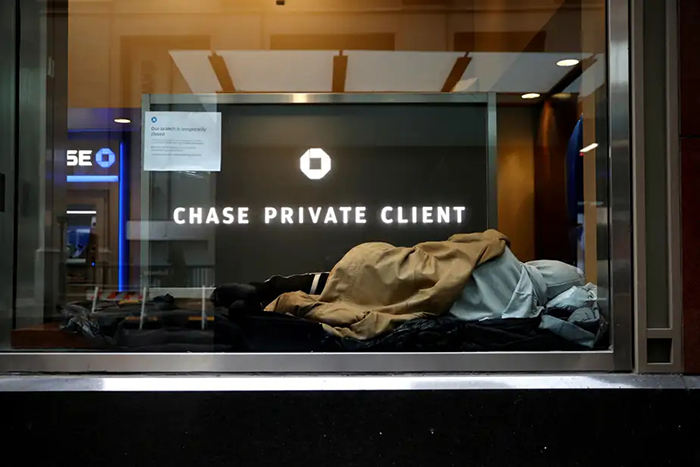 Photo d'un itinérant dormant dans la vitrine d'une banque.